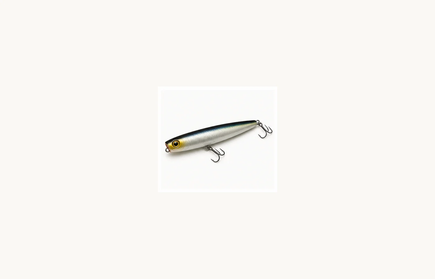 Cigar-shaped walking topwater plug with a silver body and treble hooks.